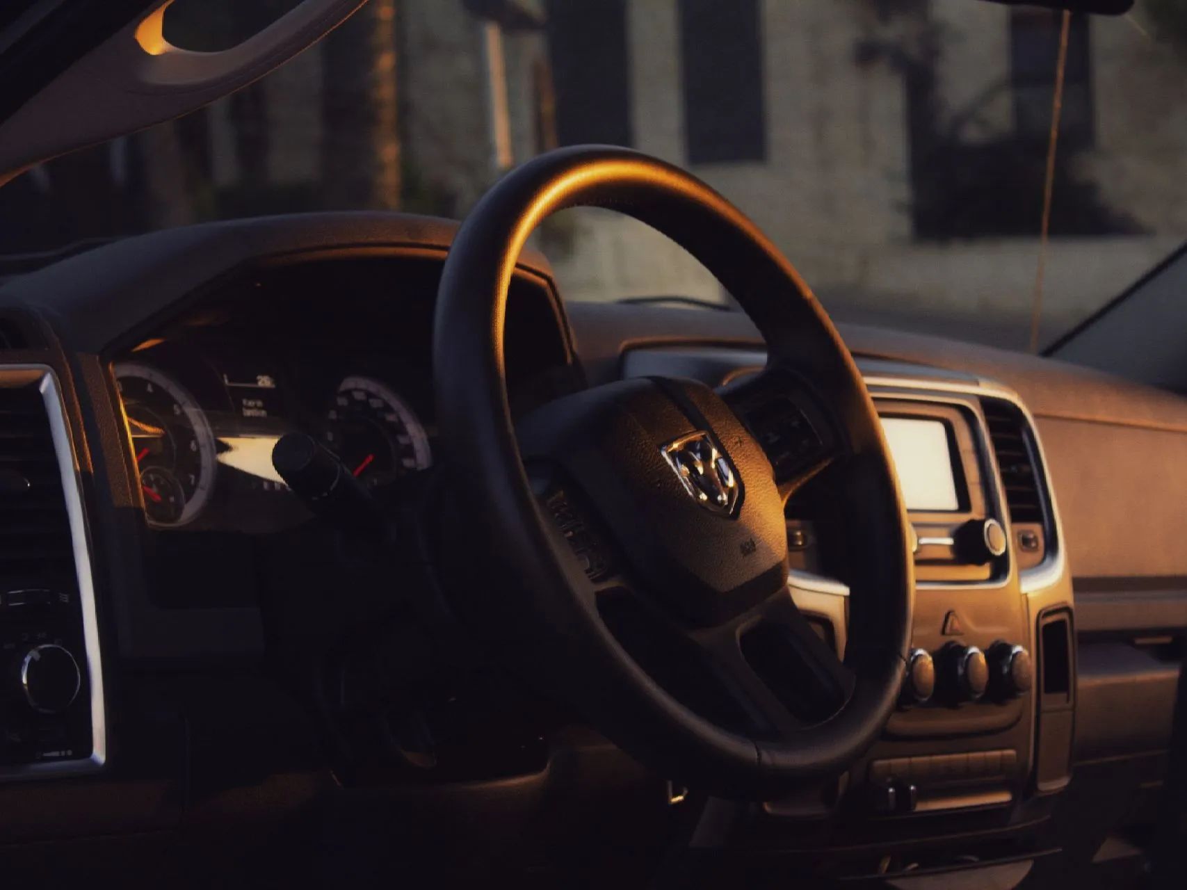 Car interior with steering wheel, dashboard, and center console in warm sunlight