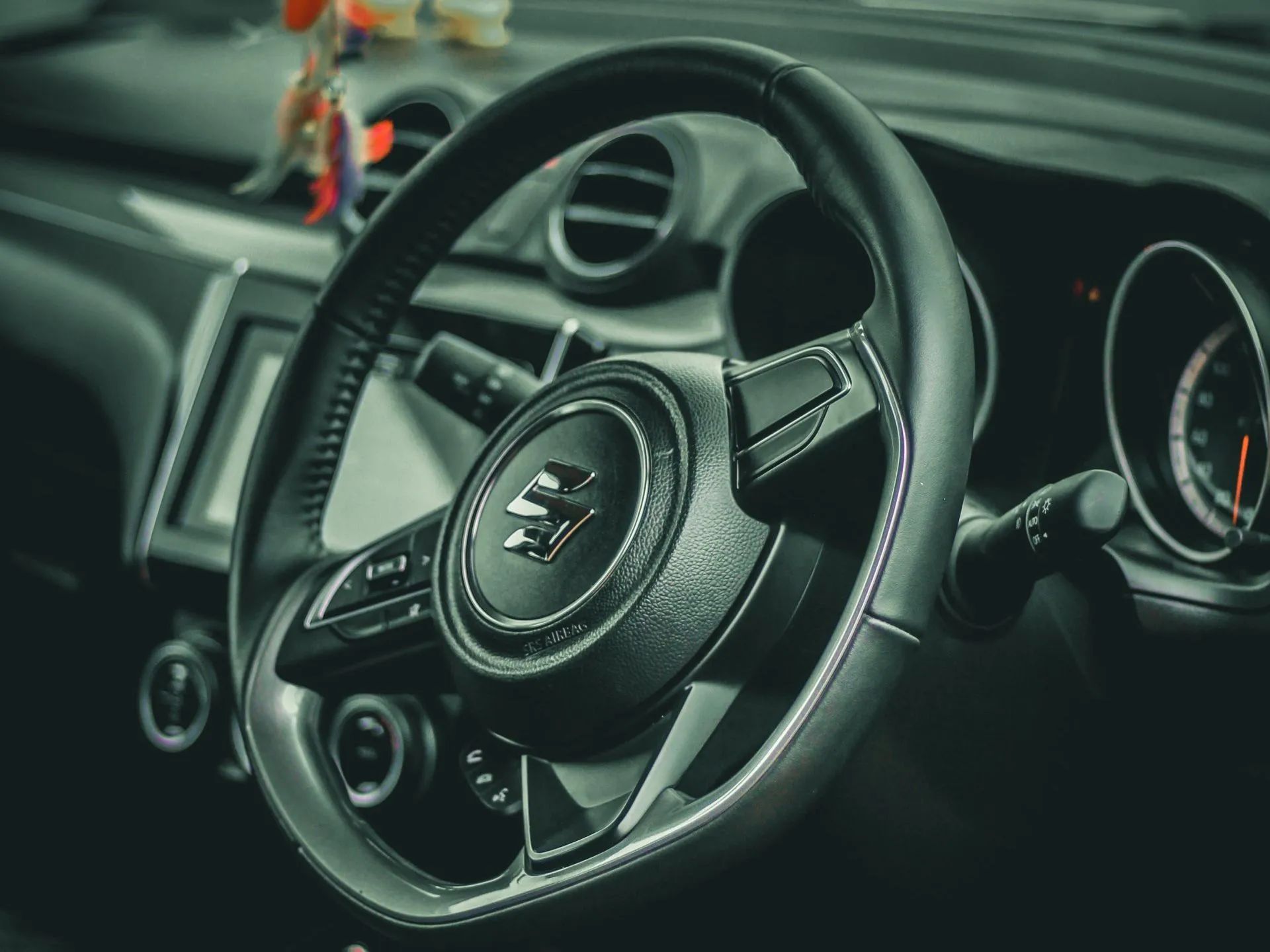 Close-up of a black car steering wheel and dashboard with gauges in a sleek interior