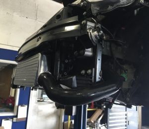 Close-up of a black vehicle undercarriage and exhaust in a garage lift