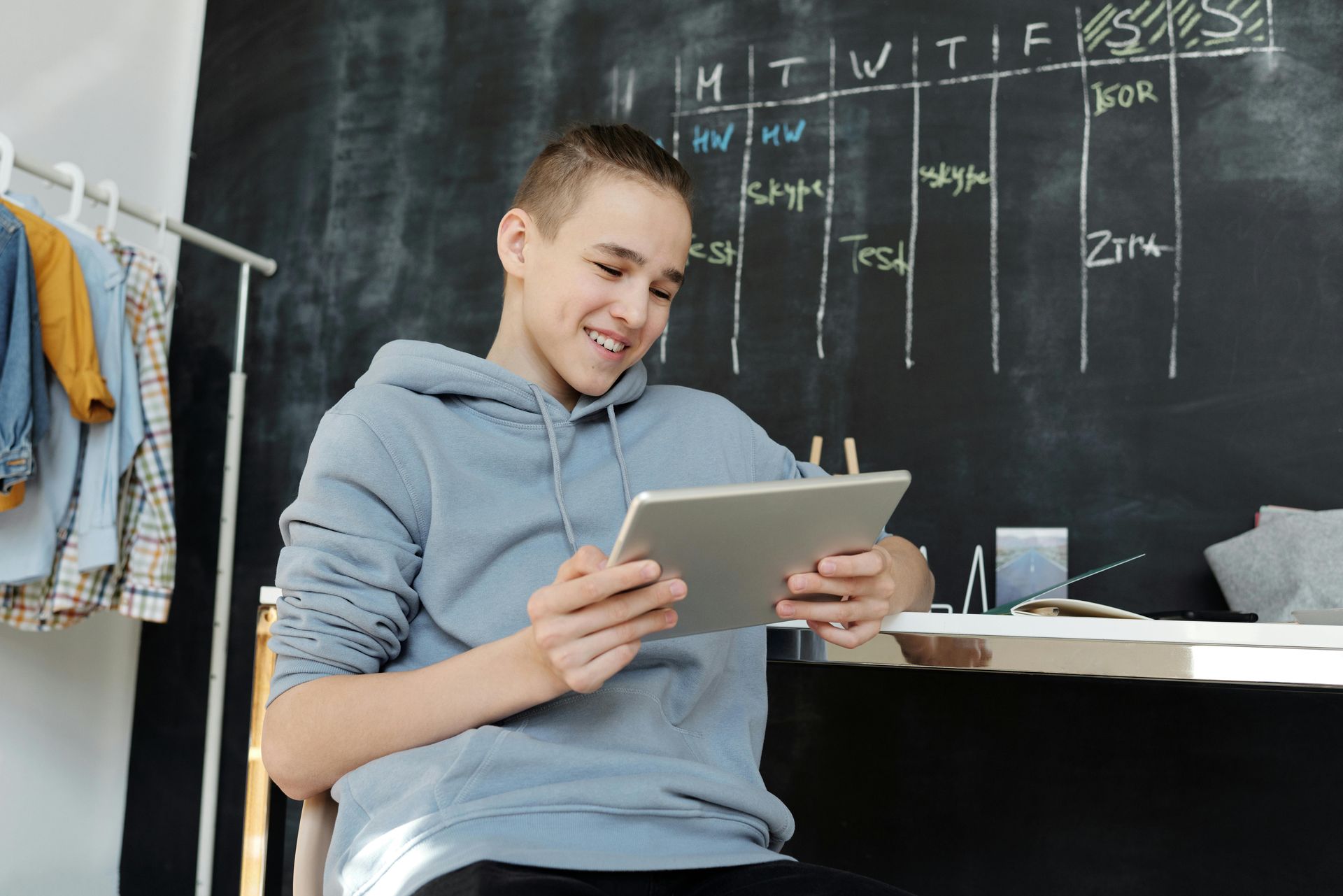 A teen learning at home on a tablet sitting at a desk.