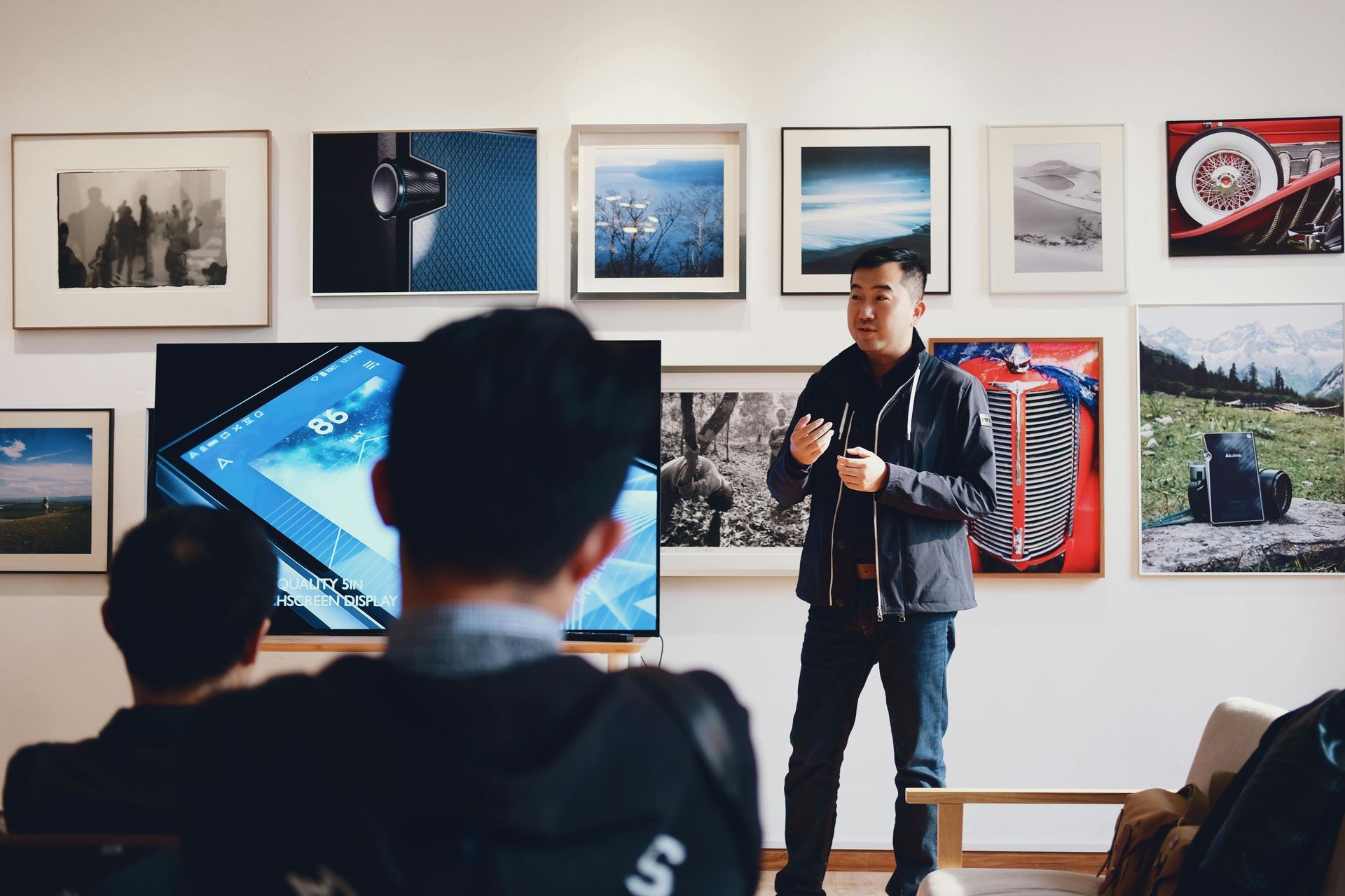 Man giving a presentation to an audience in a room with art on the walls.