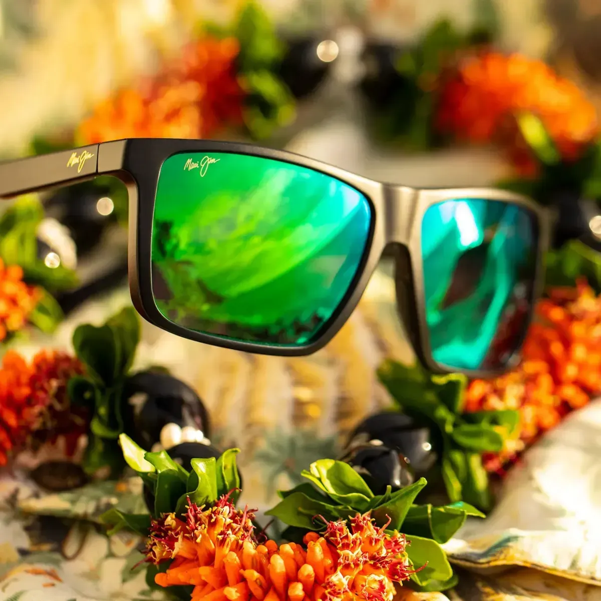 Black sunglasses with green mirrored lenses resting among orange flowers and greenery