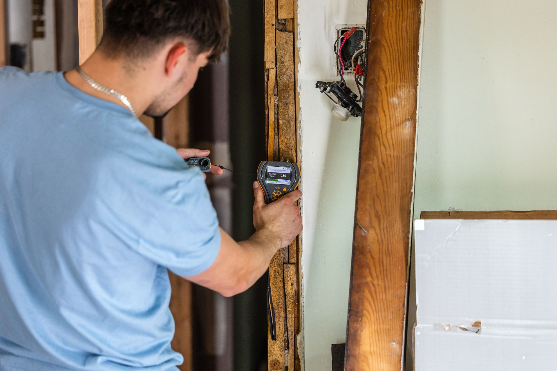 Person using a laser measure on a wooden post indoors