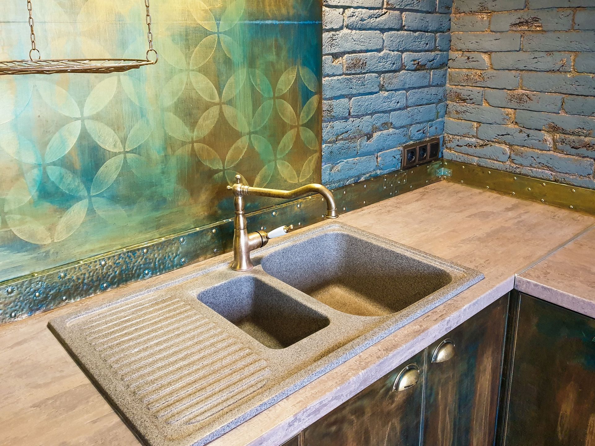 Open kitchen sink cabinet showing plumbing pipes and water damage on the cabinet floor