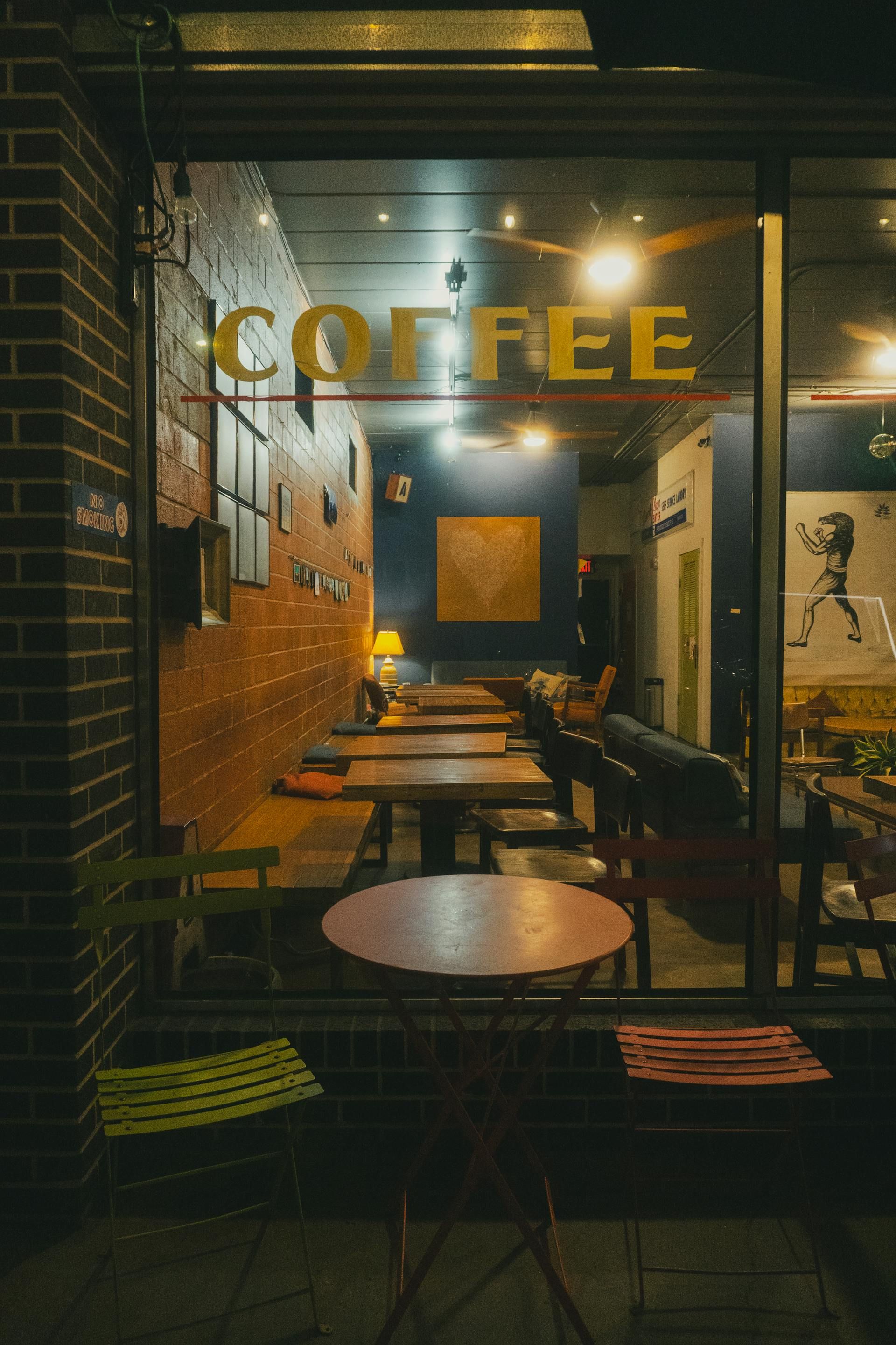 Coffee shop window at night. Tables and chairs inside, 