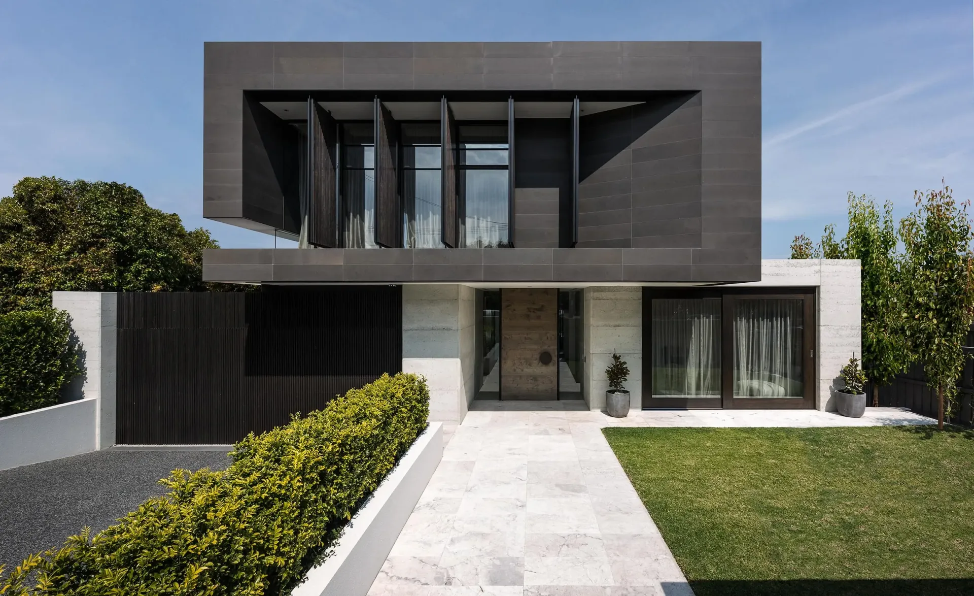 A modern house with a lot of windows and a walkway leading to it.