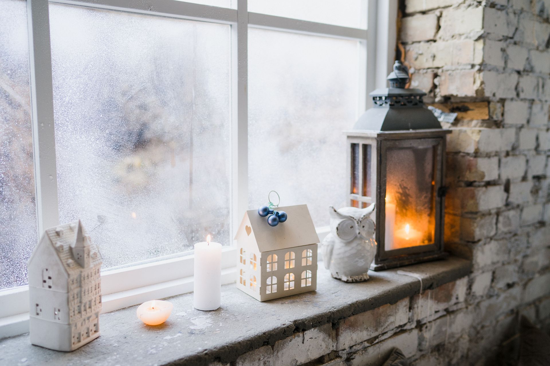 There are candles and lanterns on the window sill.