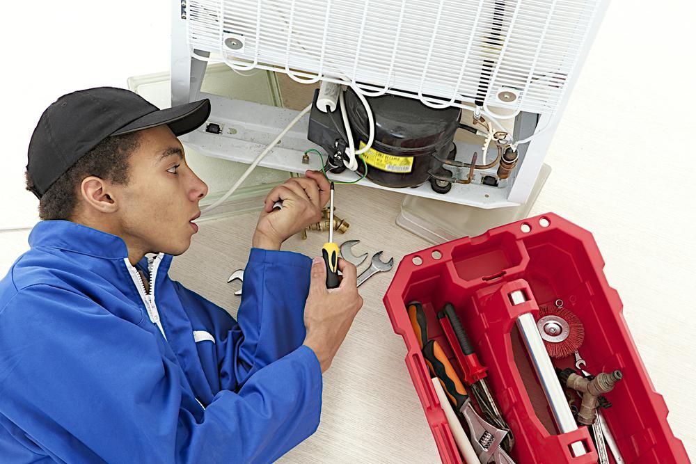 A Repairman Undergoing Refrigerator Maintenance — North West Heating, Cooling and Refrigeration in Taminda, NSW
