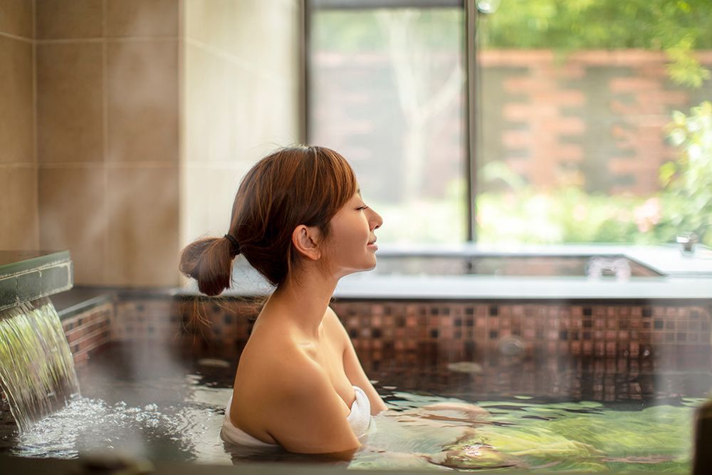 A Woman Is Taking A Bath In A Hot Tub — North West Heating, Cooling and Refrigeration in Narrabri, NSW