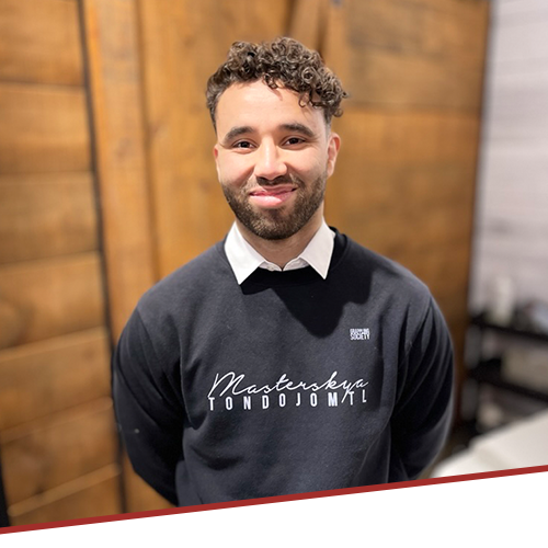 A man with curly hair and a beard is wearing a black sweater with the word masters on it.