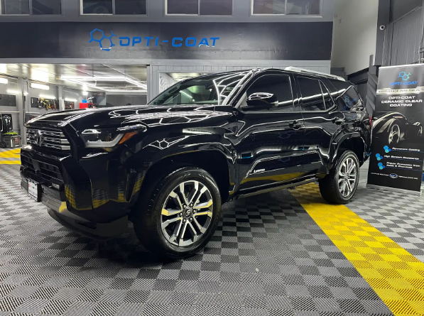 Black SUV in a car detailing shop with glossy finish, parked on a checkered floor under bright lights