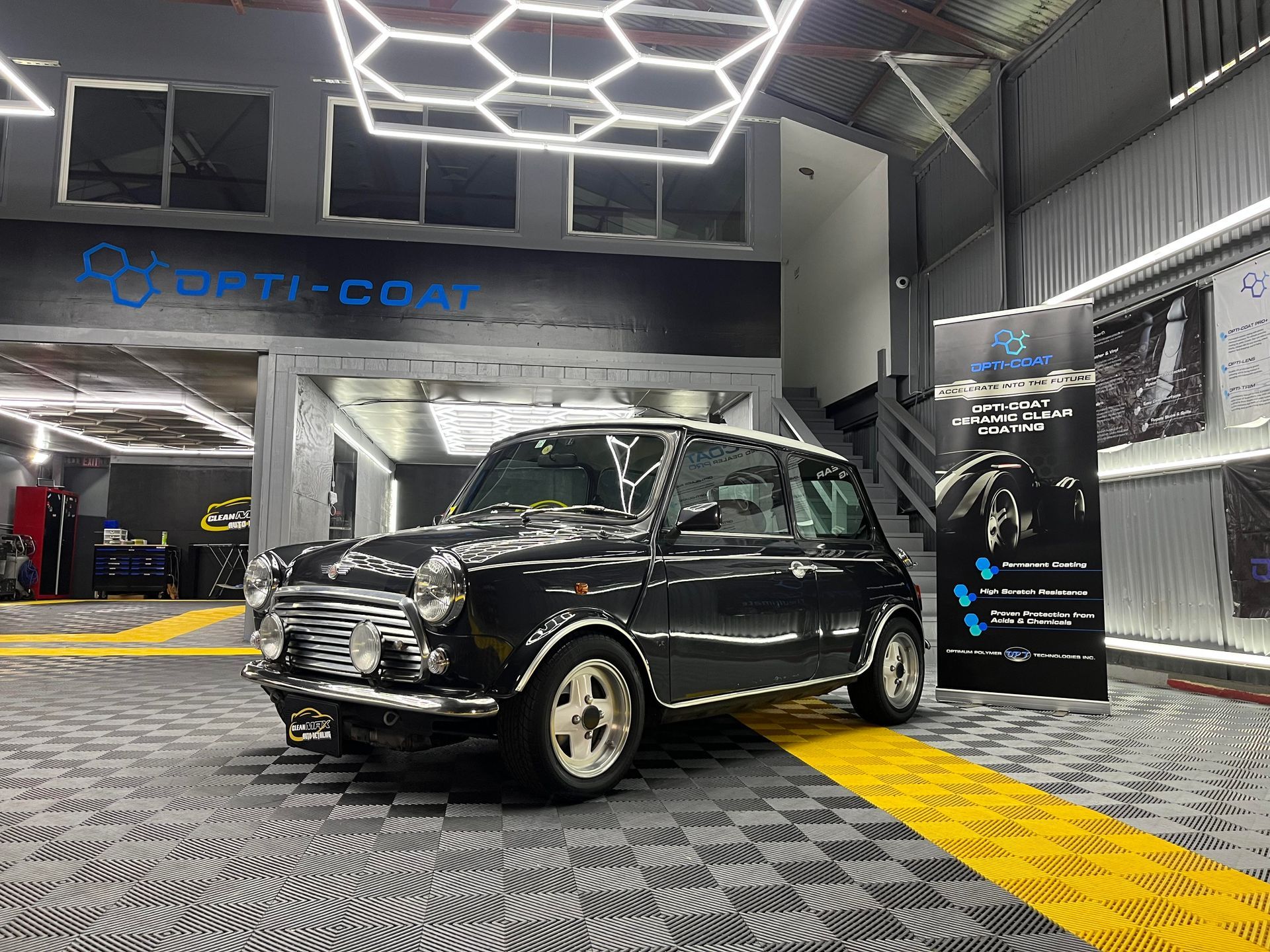 Black vintage Mini Cooper in a modern showroom with geometric ceiling lights