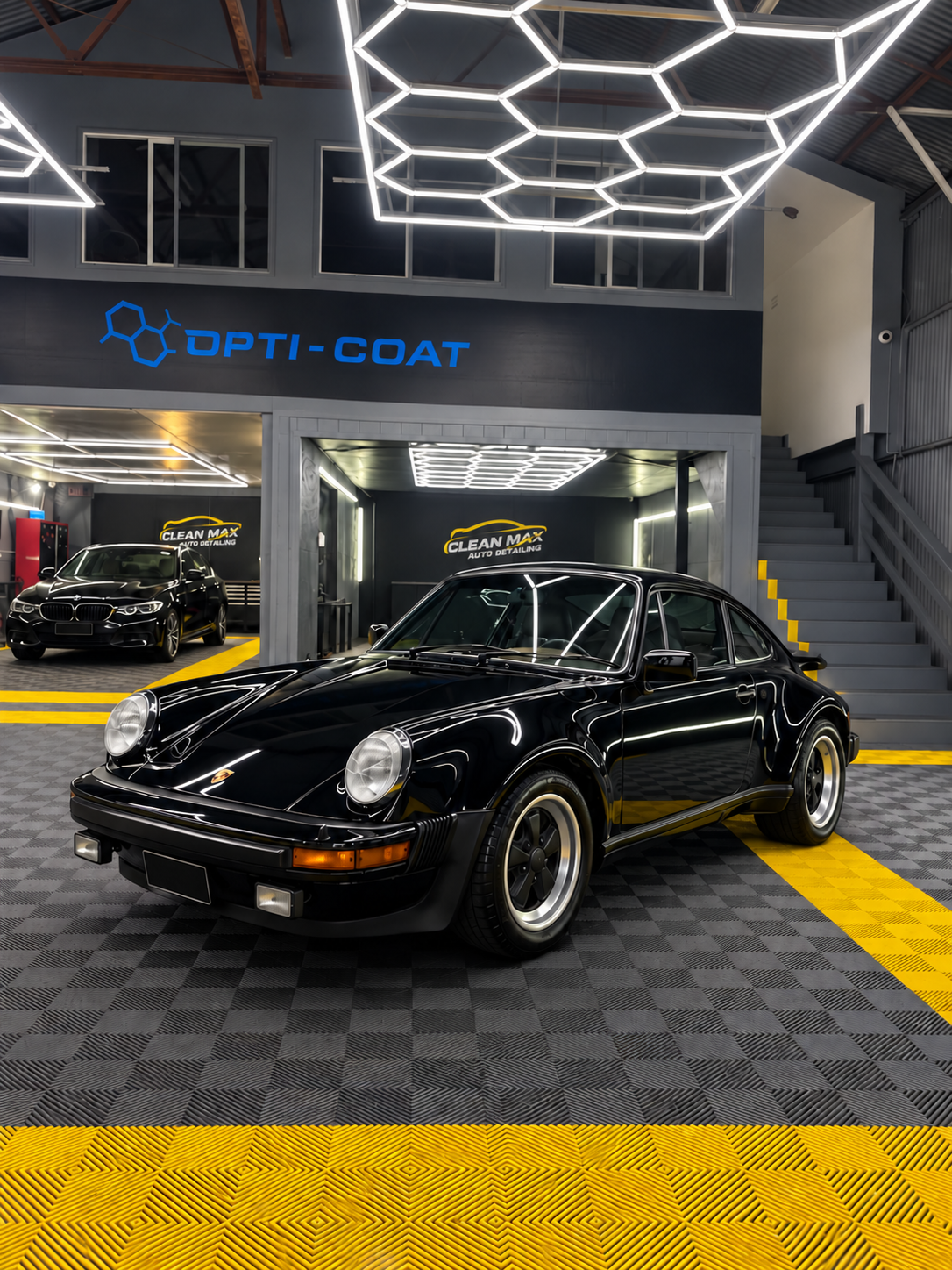 Black classic Porsche in a car detailing garage with geometric ceiling lights and yellow-black floor mats