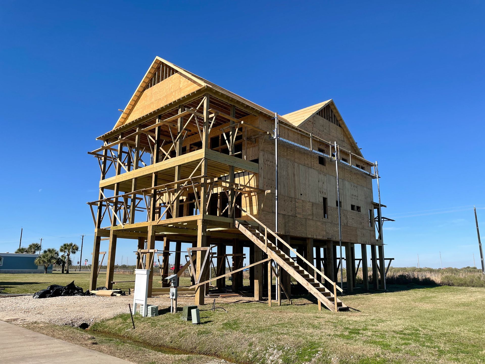 A house being built with wooden slabs and a ladder under a blue sky. A house being built with wooden slabs and a ladder under a blue sky.