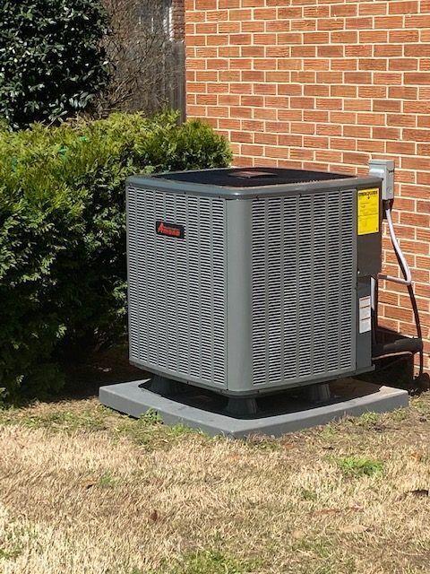 An air conditioner is sitting outside of a brick building.