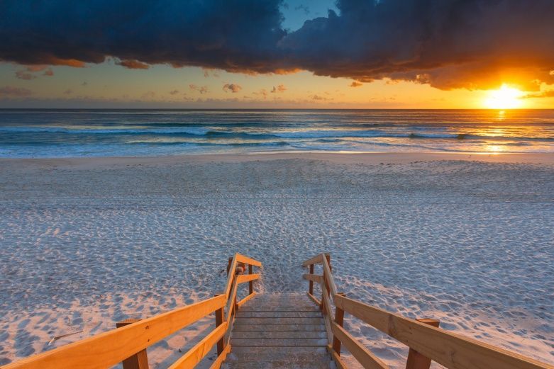 A Wooden Walkway Leading To The Beach At Sunset — Dazzling Blue Pool & Spa Centre Gold Coast in Mermaid Waters, QLD