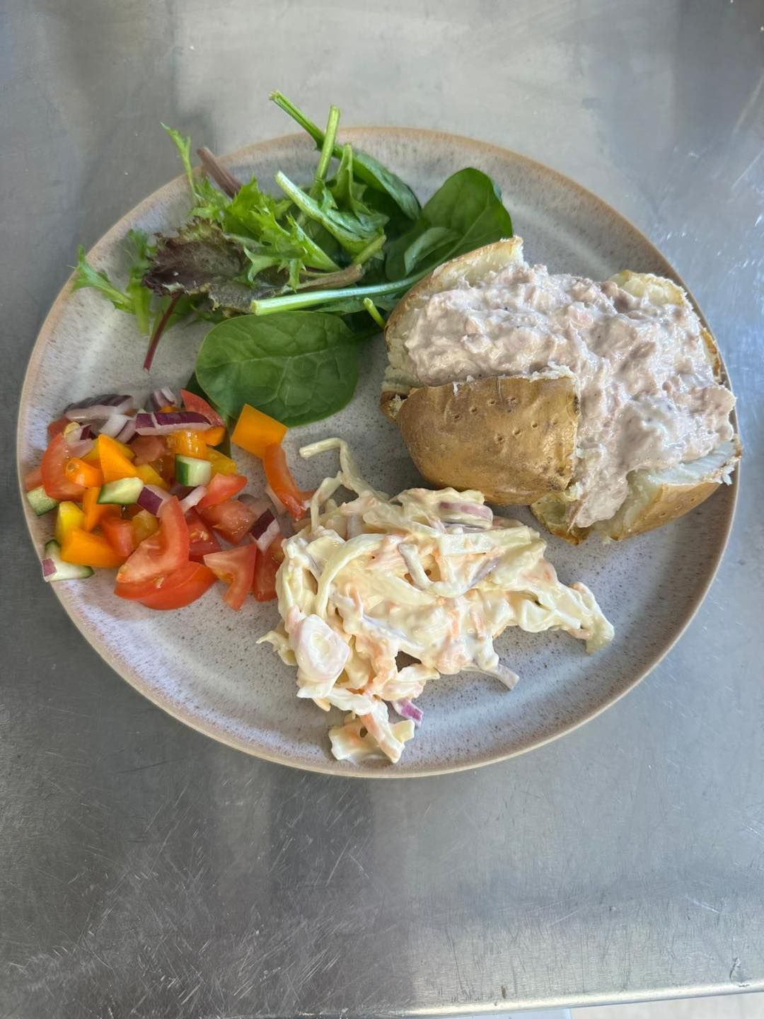 Baked potato with tuna, side salad, coleslaw on a plate.