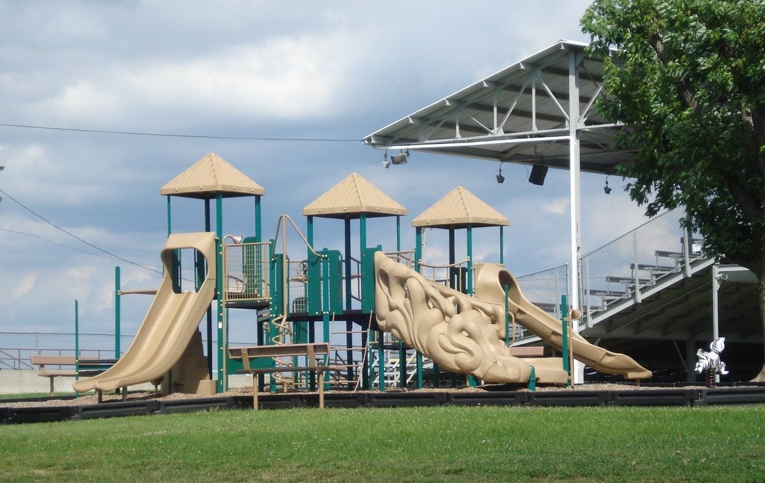A playground in a park with a stadium in the background