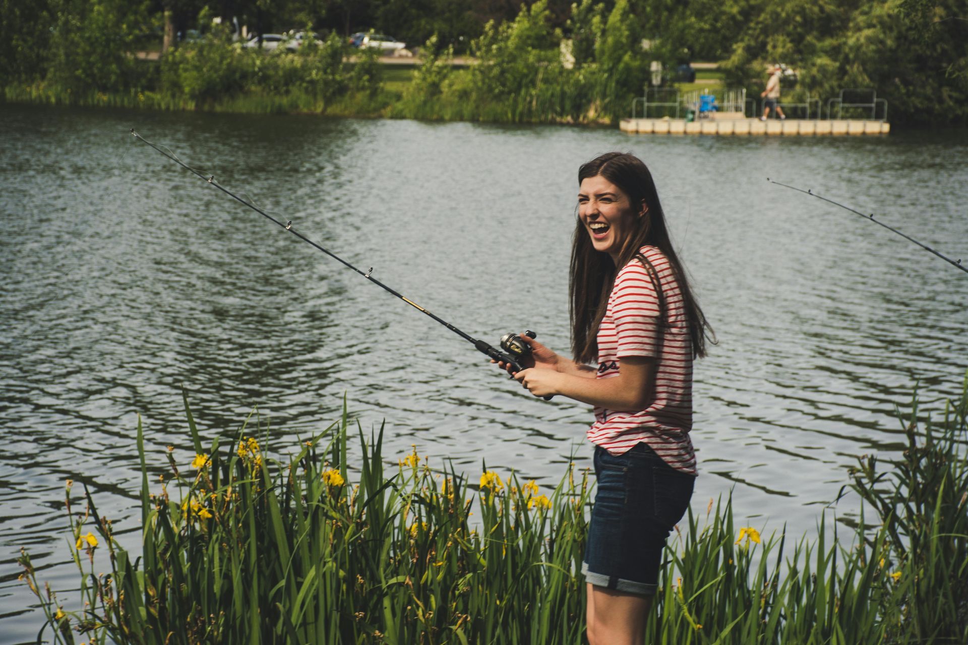 A woman is fishing in a lake with a fishing rod.