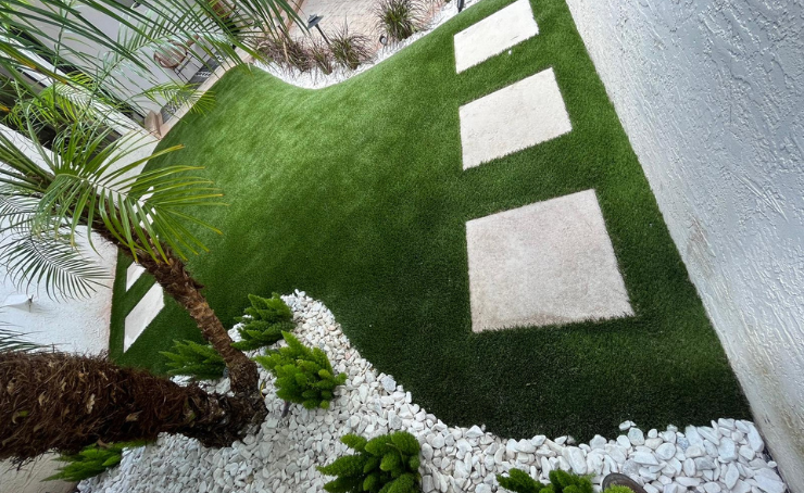 A lush green garden with white rocks and a palm tree.