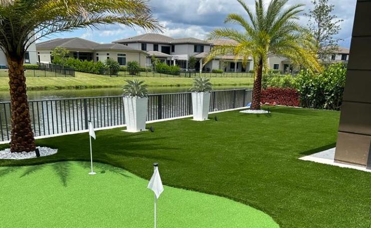 There is a putting green in the backyard of a house.