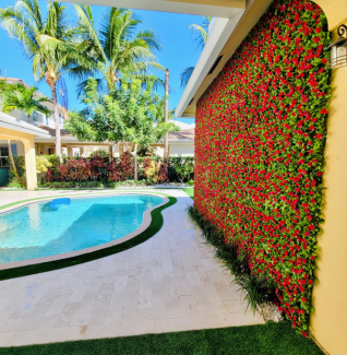 A swimming pool is behind a wall with red flowers