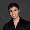 A young man in a black shirt is smiling for the camera.
