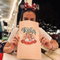 A woman is sitting at a table holding a tony 's bag in front of her face.