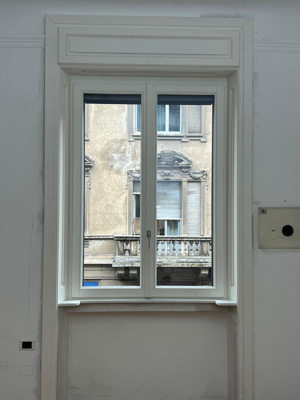 Finestra interna bianca con vista su un vecchio edificio beige all'esterno