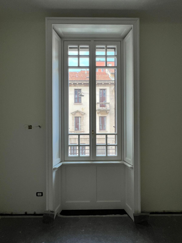 Un'ampia nicchia con finestra in una stanza vuota, affacciata su un edificio dall'altra parte della strada.