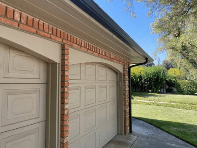 A garage with a brick wall and a white garage door