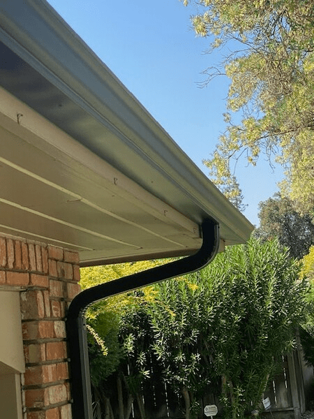 A black gutter is on the side of a house.