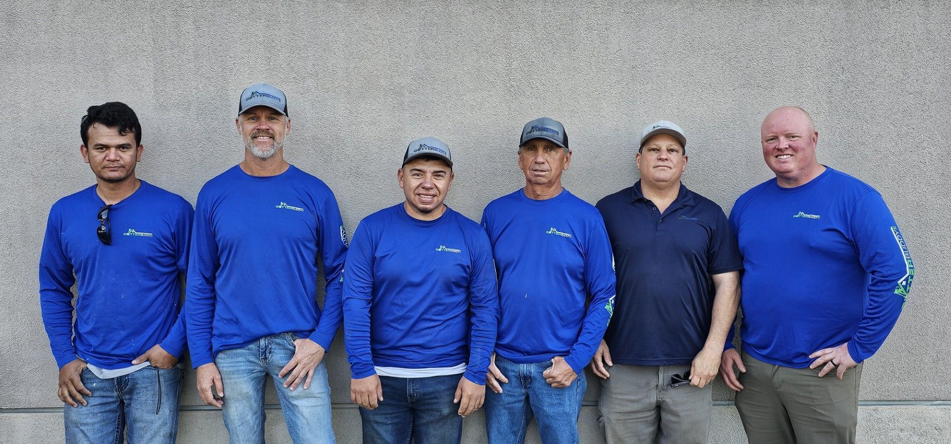 A group of men standing next to each other wearing blue shirts.