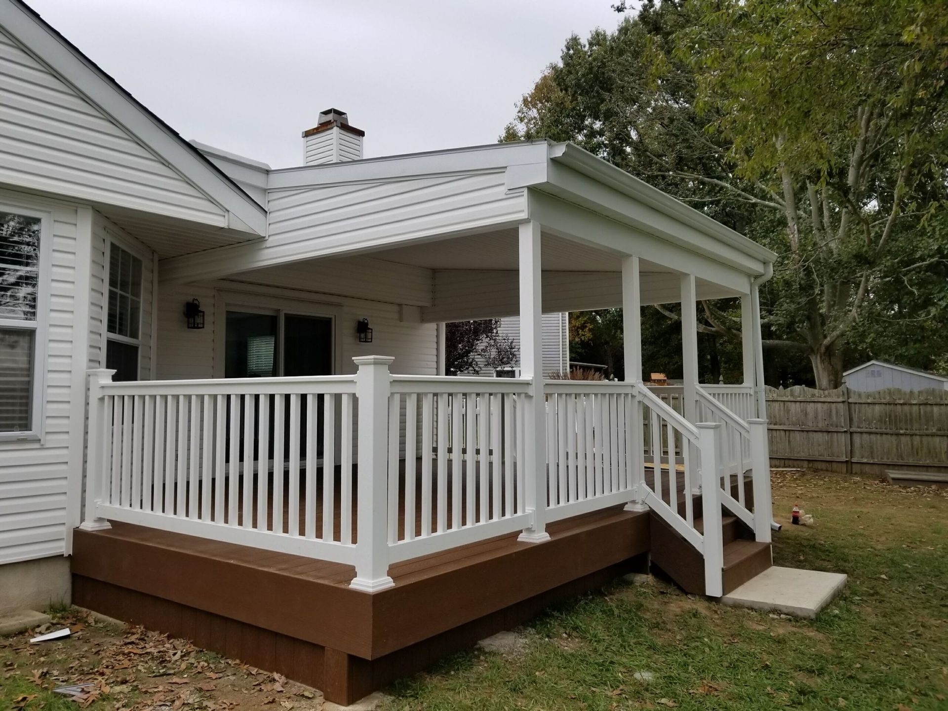 White-railed wooden porch with steps attached to a house and screened-in covered deck