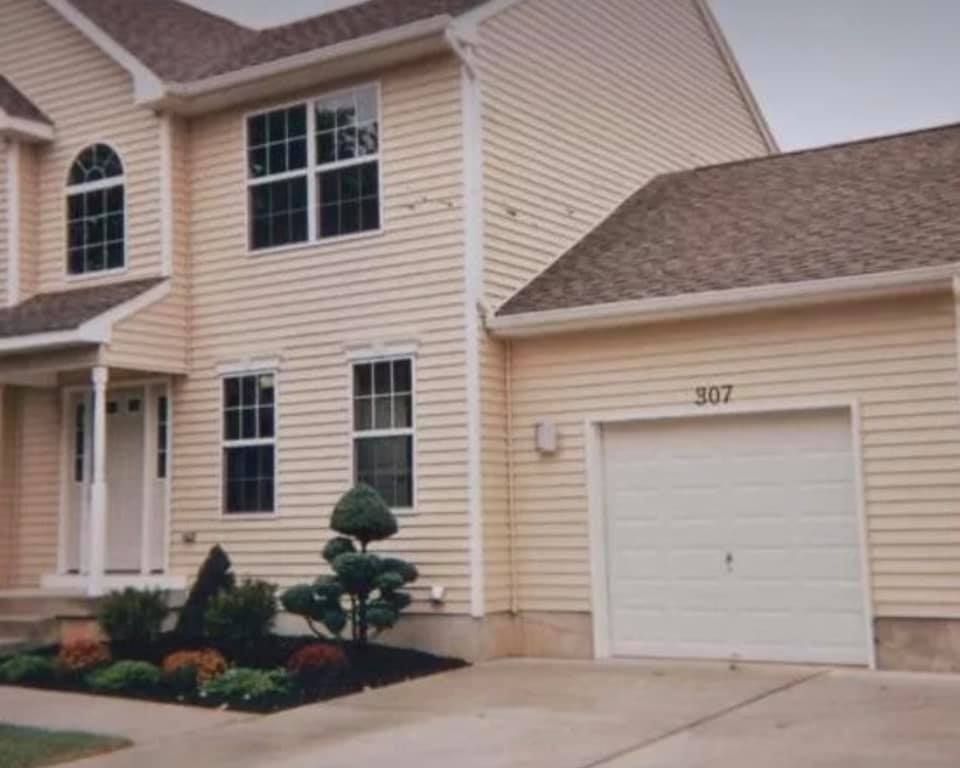 Suburban townhouse exterior with beige siding, garage door 307, and landscaped front yard
