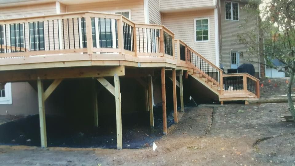 Raised wooden deck and stairs attached to a house, with open space underneath.