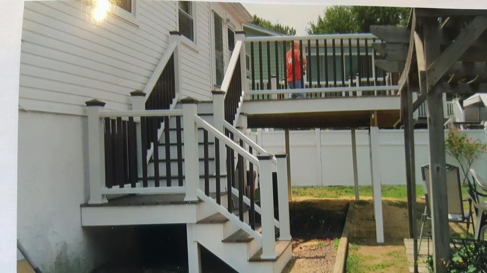 Back porch and deck with white stairs; a person in a red shirt stands on the upper deck.