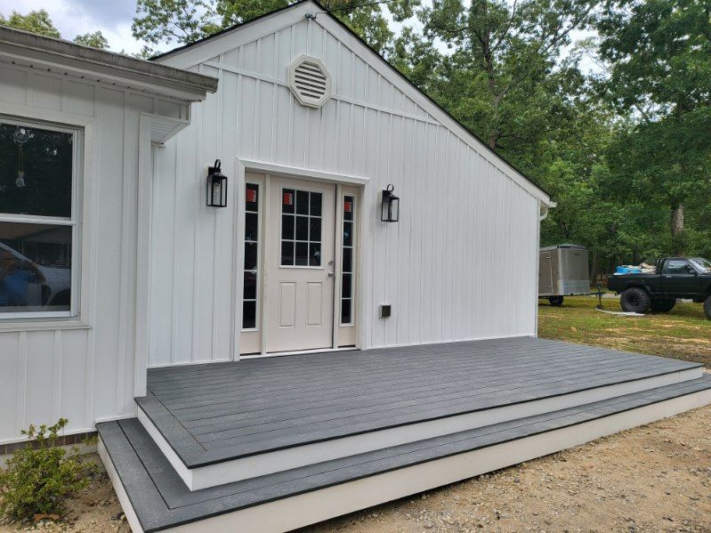 White house exterior with double doors and a raised gray deck or ramp in front