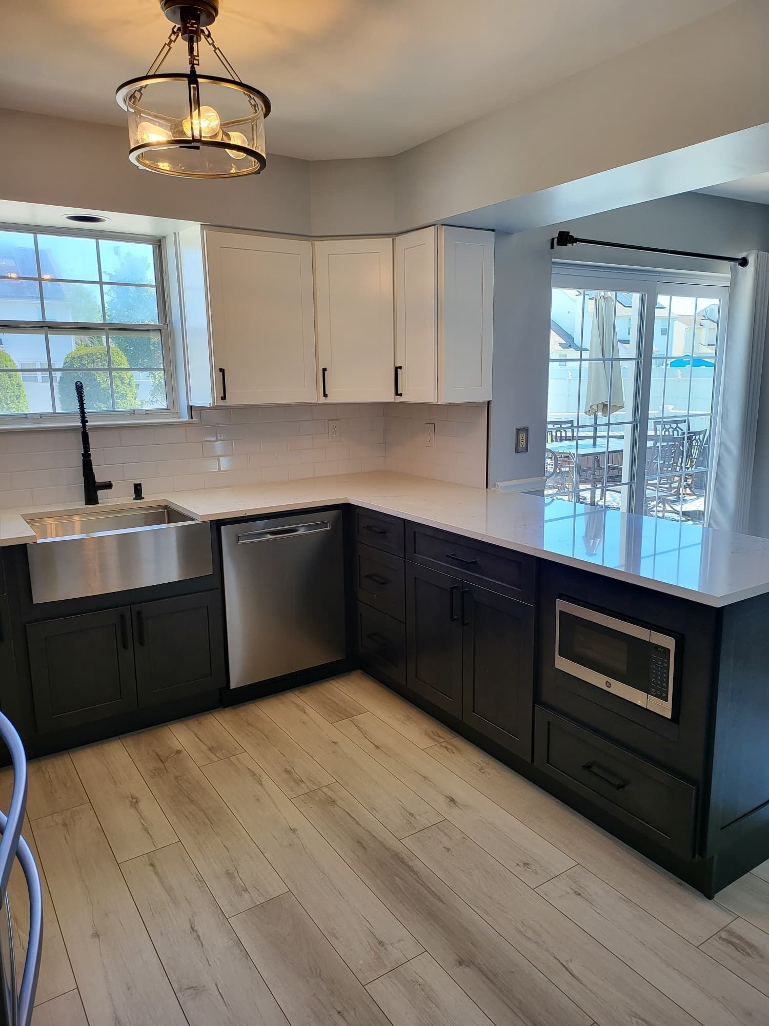 Bright kitchen with black cabinets, white countertops, stainless dishwasher, and large windowed corner.