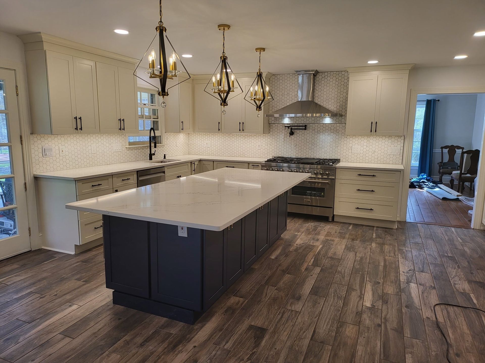 Modern kitchen with a large island, white cabinets, pendant lights, and wood-look flooring.