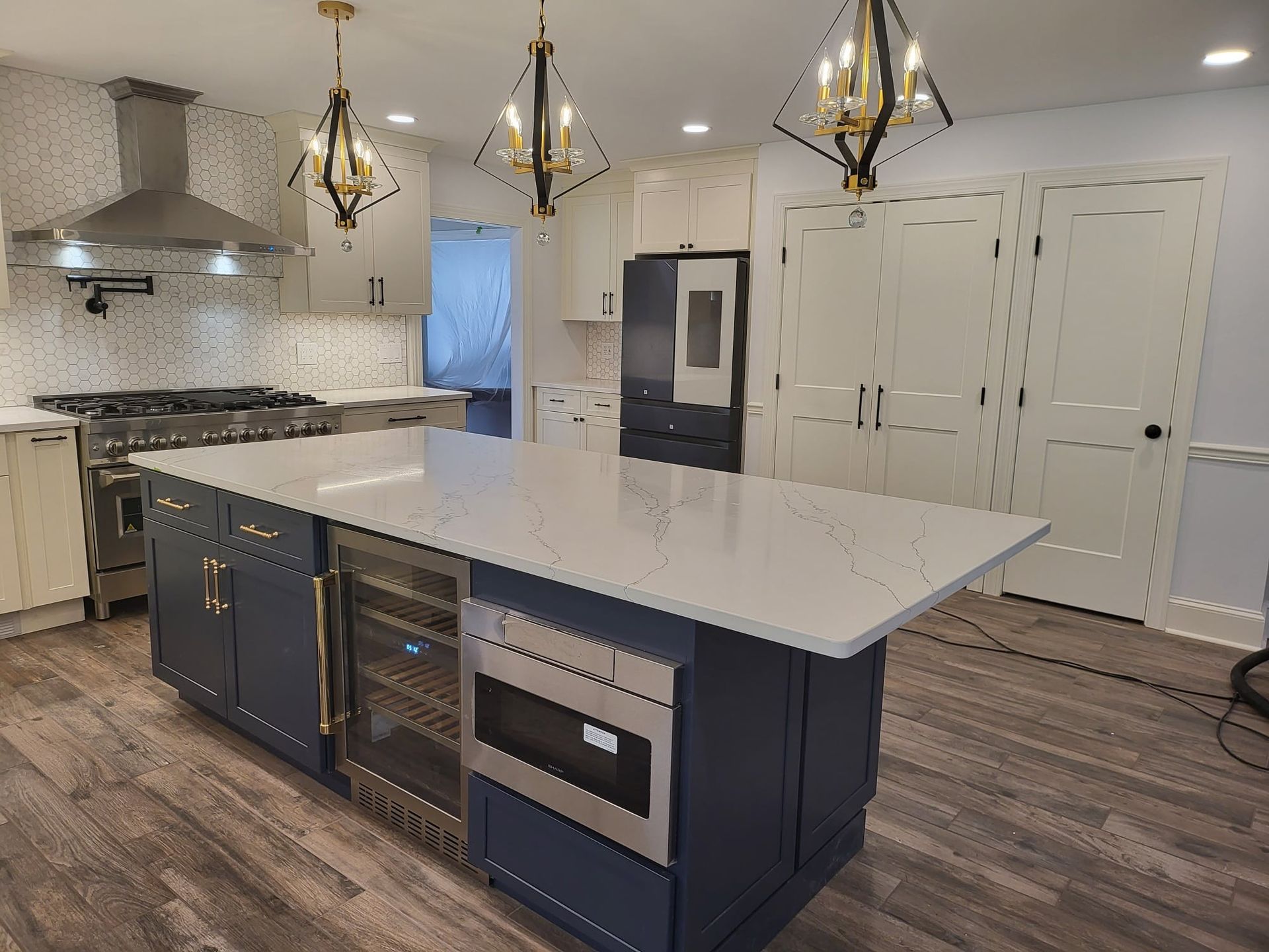Modern kitchen with large island, white quartz countertops, dark blue cabinets, and pendant lights