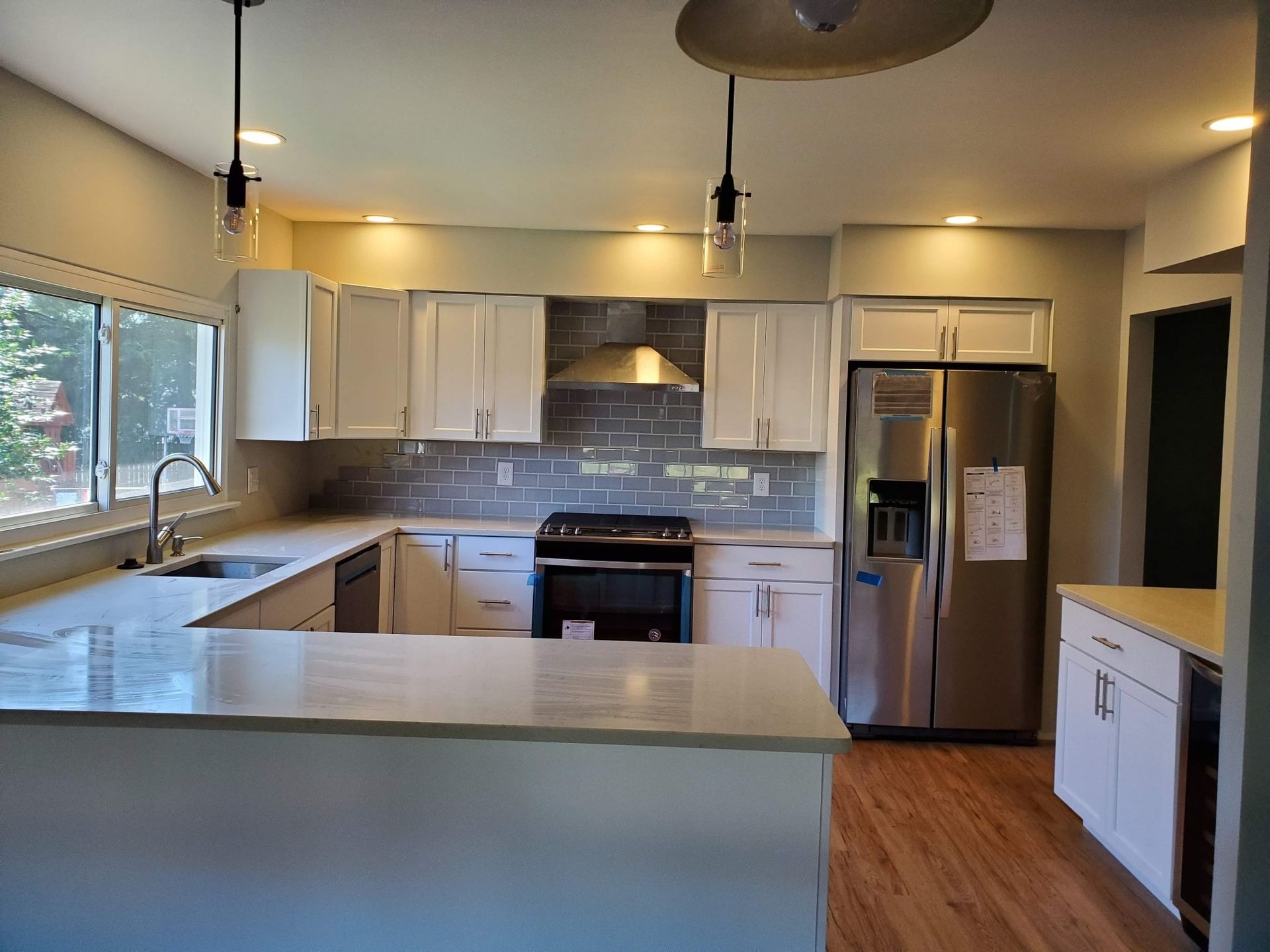 Bright, modern kitchen with white cabinets, stainless steel appliances, island, and wood floors.