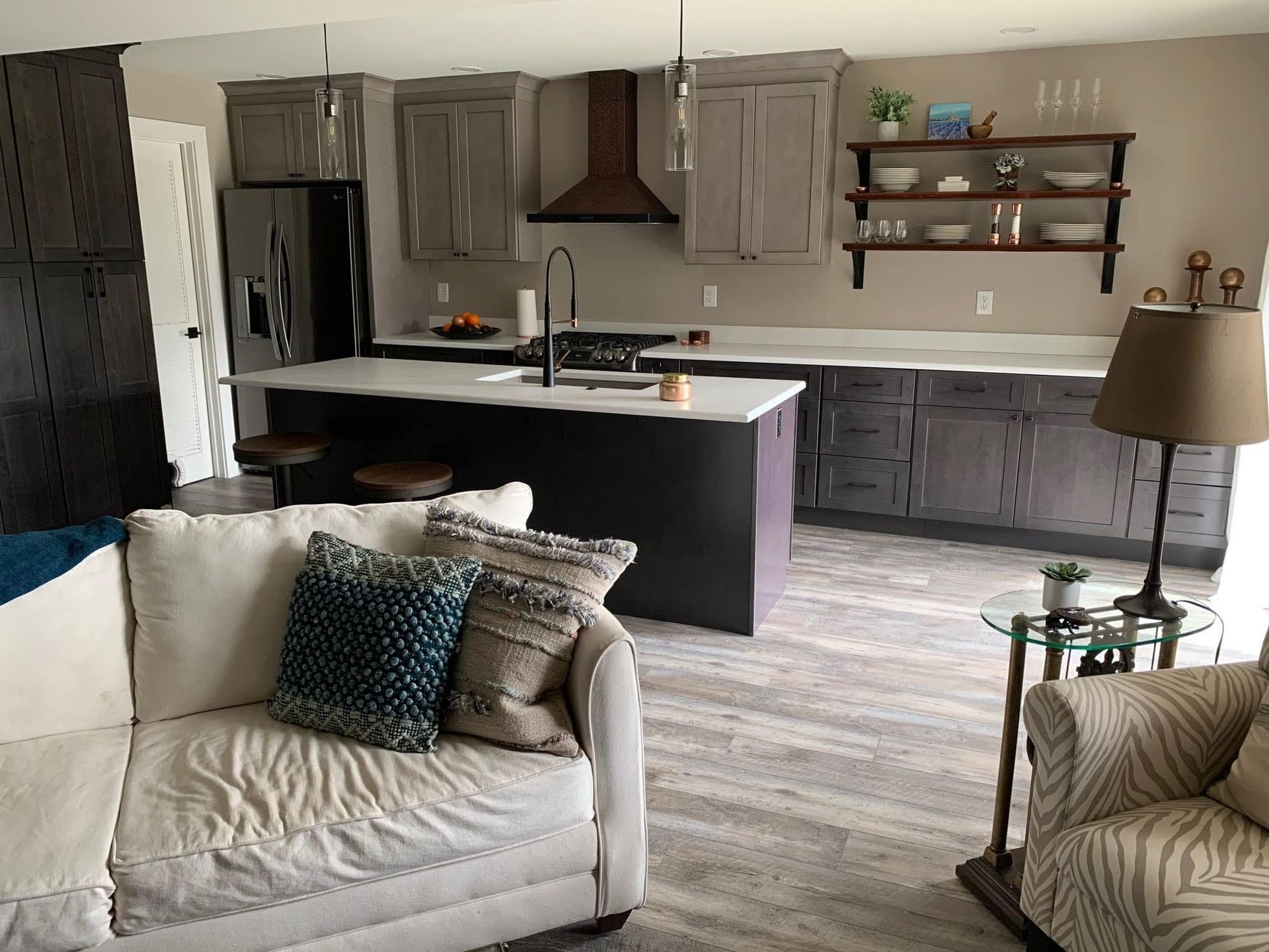 Open-concept living room and kitchen with white sofa, gray cabinets, island, and beige armchair