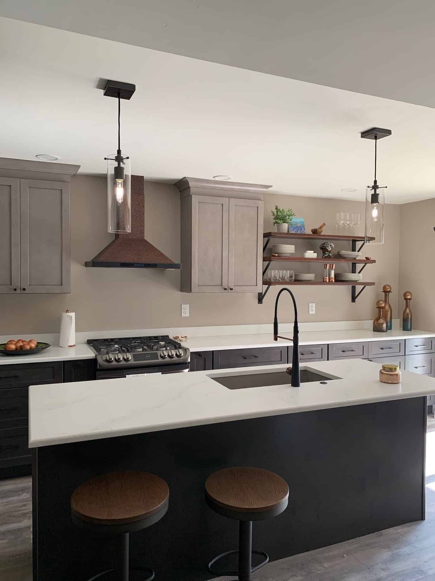 Modern kitchen with black island, white countertops, gray cabinets, open shelves, and pendant lights