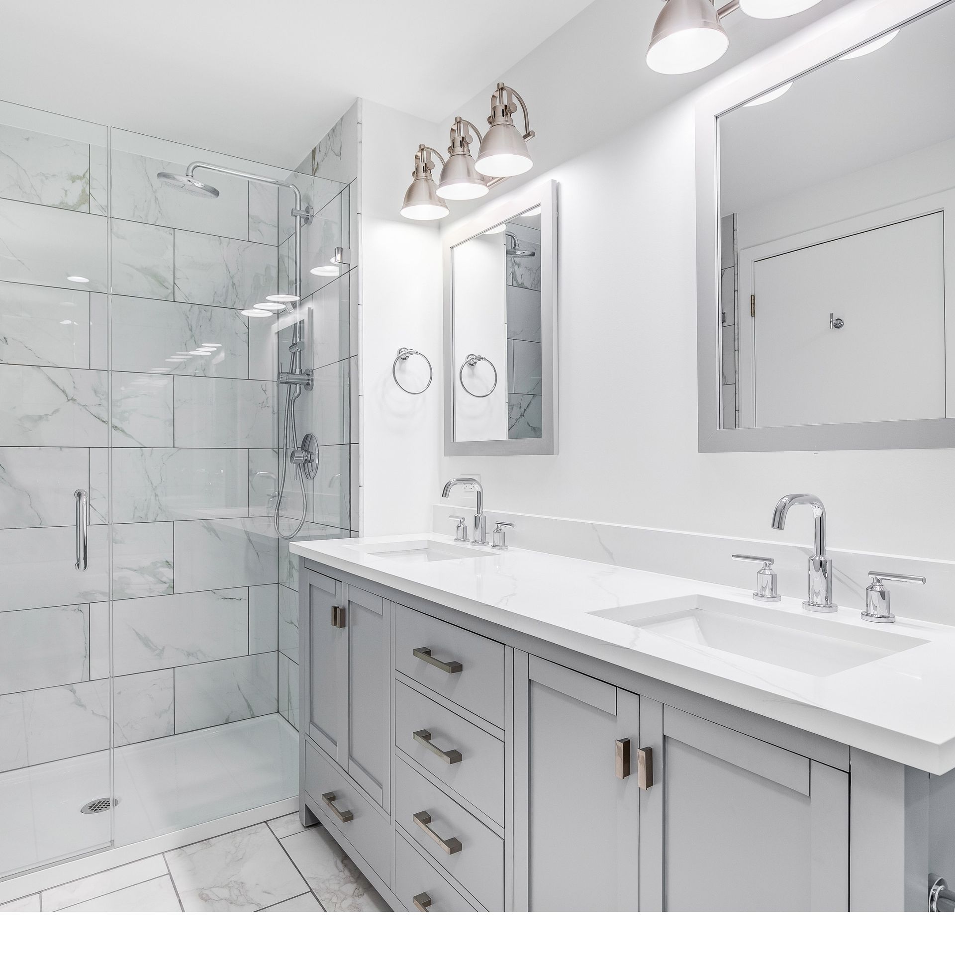 Bright white modern bathroom with double vanity, mirrors, and glass walk-in shower
