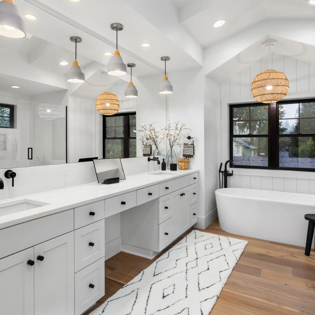 Bright modern bathroom with white double vanity, freestanding tub, black-framed windows, and wood floor