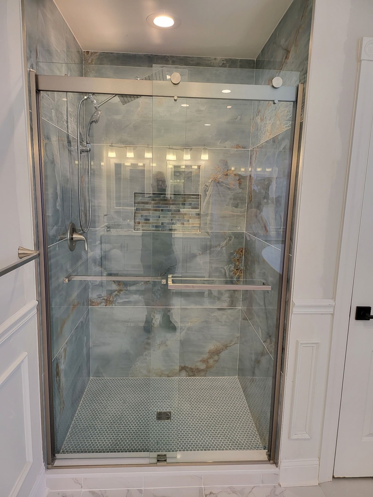 Glass elevator lobby with mirrored walls, metal handrails, and bright overhead lights