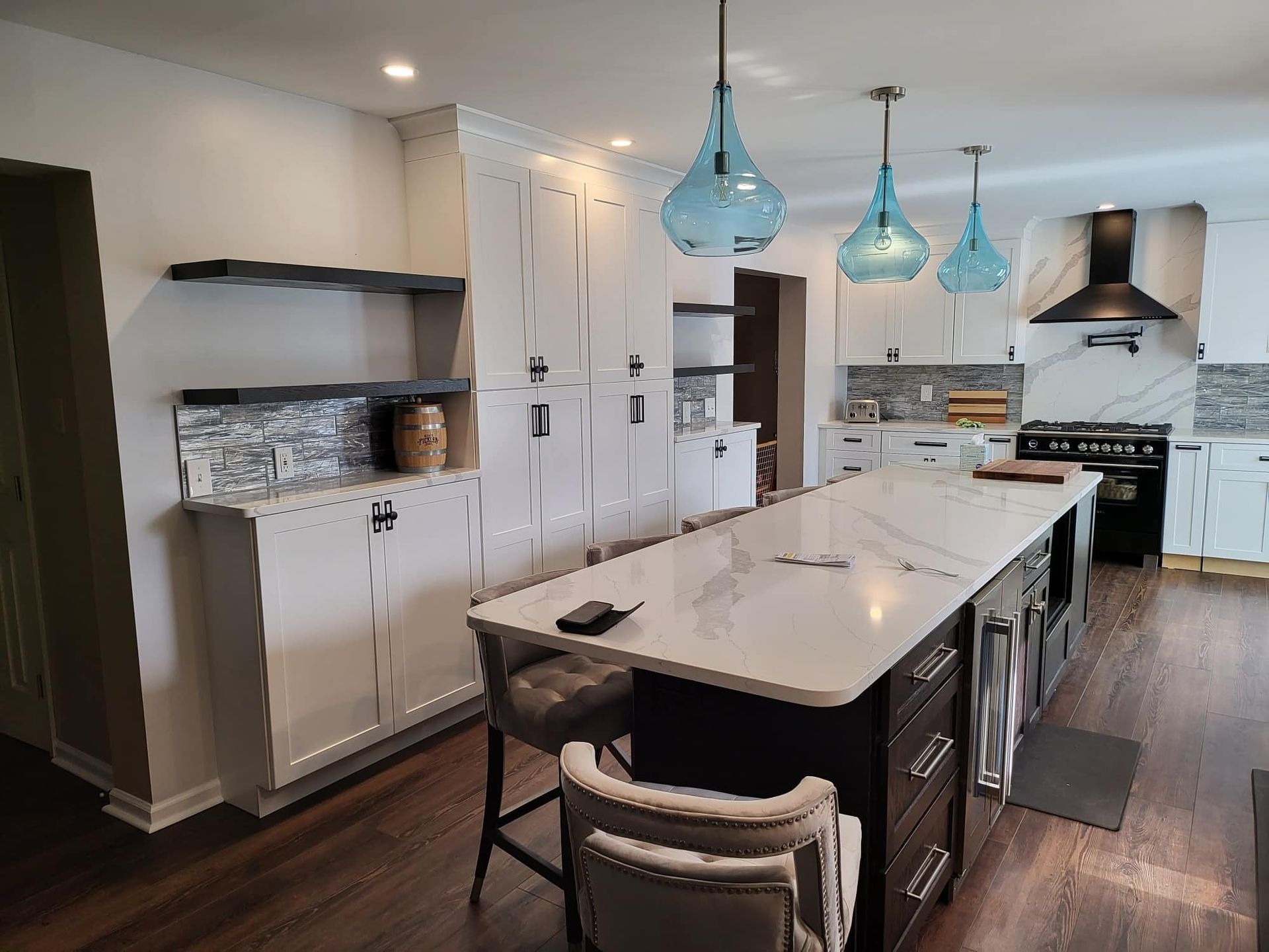 Modern kitchen with a large island, white cabinets, blue pendant lights, and stainless steel appliances