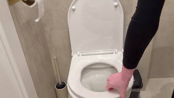 Person in pink socks standing on a toilet seat in a bathroom
