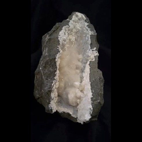 Una grande roccia con un buco su uno sfondo nero.